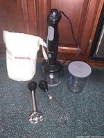 Full lot laid out including the immersion blender motor handle, blending shaft, whisk attachment, chopping container with lid, and storage bag.