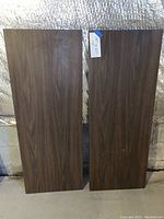 Two rectangular dark wood grain laminated boards standing vertically, visible width and grain pattern, minimal wear.