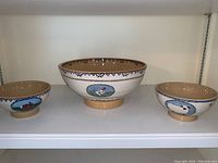Three Nicholas Mosse pottery bowls on shelf, featuring animal motifs and Spongeware style decorative borders.