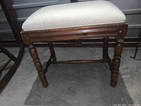 Full side view of bench showing padded seat and turned wooden legs.