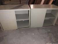 Front view of two steel cabinets with sliding doors, one open showing shelves, the other door closed.