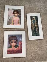 Three vintage Keane art prints on board arranged on carpet, includes three black frames and one brass floral frame