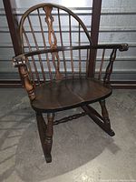 Front view of the vintage Windsor rocking chair showing scroll arms, spindle back, turned legs, and wooden rockers.