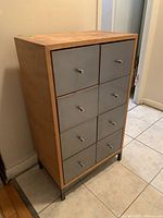 Front angle view of vintage octagonal dresser with wood frame and gray metal front drawers, placed on small metal legs.