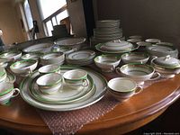 Full view of various cups, saucers, and plates arranged on a wooden table showing the pattern and condition of the set.