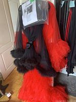 Two lingerie style dressing gowns hanging, black one with feathery trim over the red ruffled long gown