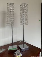 Pair of chrome and crystal bead table lamps side by side on a surface with LED batteries in front.