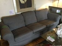 Three-quarter view of the three-seater sofa in gray showing condition and fabric texture.