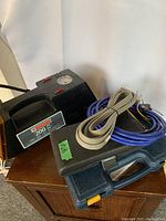 Electric air pump, coiled cables and two closed tool cases on cabinet
