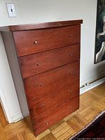 Front view showing full dresser with five drawers closed, cherry stain finish and metal pull knobs.