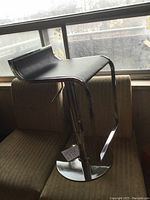 Front angled view of vintage black vinyl and chrome pedestal stool showing seat and base design.