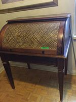 Front view of vintage solid wood roll-top secretary desk showing closed tambour door with woven wood pattern.