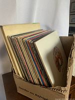 Box containing a collection of vintage vinyl records with various album covers visible at the top edge.