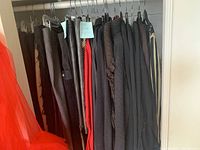 Various black and dark-colored pants and skirts on hangers