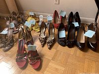Wide view of 10 pairs of varied women's shoes on parquet floor with overlay tags showing size details.