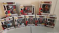Photo showing all eight Funko Pop figures in boxes including Clown Deadpool, Deadpool as Bob Ross, Deadpool the Duck, Wizard Deadpool, Bedtime Deadpool, Pandapool, Samurai Deadpool.