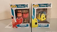 Photo showing both Sebastian and Flounder boxed vinyl figures side by side.