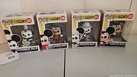 Front view of the four boxed Funko Pop Mickey figures: Steamboat Willie, Apprentice Mickey, Firefighter Mickey, and Conductor Mickey.