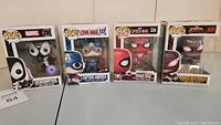 Four Marvel Pop! vinyl figures lined up in boxes: Venompool #330, Captain America #137, Spider-Man #334, Venomized Miles Morales #600.