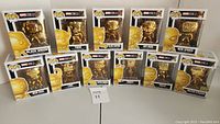 Set of 11 gold chrome Marvel Studios Pop! figures in boxes arranged on flat surface.