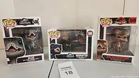 Three Funko Pop! vinyl figures from Jurassic Park/World upright in box: Velociraptor #549, Blue #586, Indoraptor #588