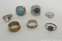 Top view of 7 silver-toned costume rings with various faux stones showcasing different designs and styles.