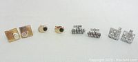 Four sets of men's cuff links arranged in a row showing different styles including gold-tone, faux onyx, coiled silver, and basket weave silver-tone.