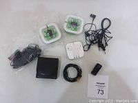 Photo of the lot including the earphones in plastic cases, Bluetooth receiver, black wired earphones, coiled cords, and black leather pouch.