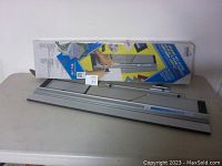 Photo of Logan Model 301-M Compact Mat Cutter along with its original box on a table showing the product setup.