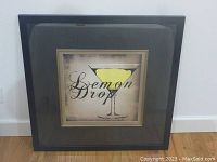 Full view of framed lemon drop print leaning against wall