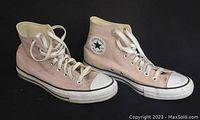 Side angle of both pink Converse Chuck Taylor high tops with visible white laces and classic logo patch.