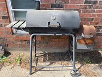 Full view of Rivergrille smoker grill showing main cooking chamber, side firebox, wheels, and stand.