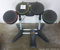 Full view of complete Guitar Hero drum set with 4 rubber drum pads set on metal stand and attached foot pedal on floor