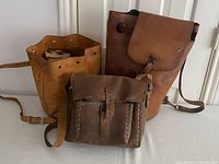 Wide shot showing all three vintage leather bags: a large bucket bag, medium bucket bag, and a dark brown satchel.