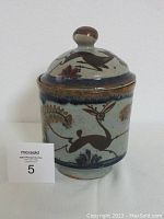 Front view of the vintage Mexican pottery jar with lid, showing detailed hand-painted animal and floral motifs.