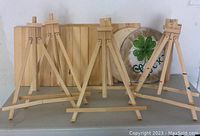 Six wooden tabletop easels in front of wood blanks