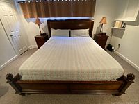 Front view of assembled king sleigh bed frame with side tables and lamps