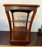 Front view showing curved legs, three shelves, and base of the occasional table