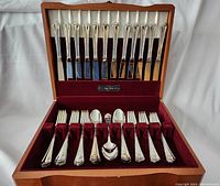 Top tray of flatware in wood storage box showing knives in upper slot and forks, spoons arranged below