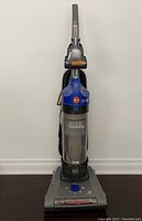 Full view of Hoover upright vacuum cleaner showing blue and gray body with attached hose and power cord.