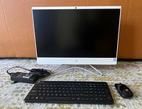 Front view of HP all-in-one on stand with keyboard, mouse, power adapter