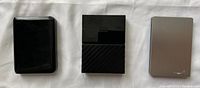 Three external 2.5 inch hard drives: Samsung, Western Digital, and Seagate placed side by side on a white surface.
