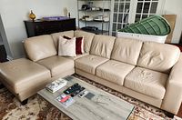 Front-left view of entire beige leather sectional including chaise and three-seat section