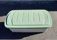 Top view of Rubbermaid plastic storage box with light green lid showing handle grooves and ribbed lid design.