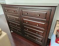 Photo showing full front view of dark wood chest with 8 drawers and round metal knobs.