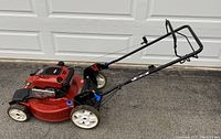 Full side view of red Toro mower showing deck, wheels, handles