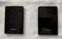 Front view of two black ADATA external hard drives side by side showing logos and surface finish.