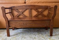Front view of wooden hallway bench showing X-cross backrest and curved armrests.