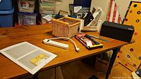 Photo of items on wooden table including wicker basket, white power bar, sidewall grill, small black box, tools in tray, and packaged flashlight