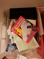 Top view of collected office supplies including black organizer tray, scissors, and document bag in packaging, with notebooks and other papers.